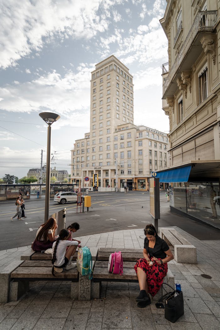Street view in Lausanne with people relaxing near a tall building.